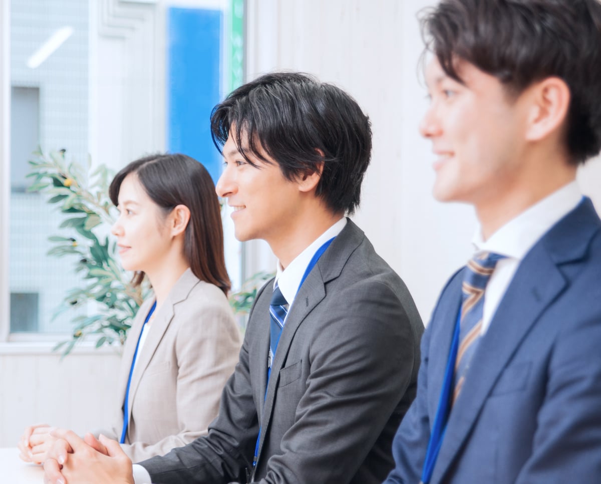 年次研修で3人の社員が傾聴しているイメージ